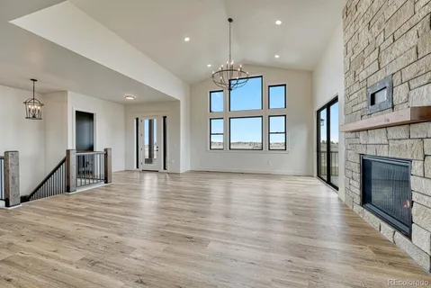 a view of an empty room with wooden floor and a fireplace