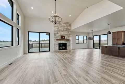 an empty room with wooden floor fireplace and windows