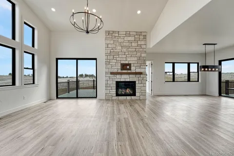 an empty room with wooden floor fireplace and windows