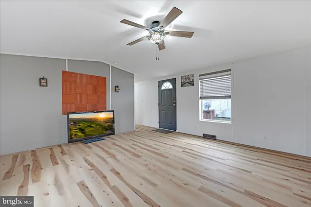an empty room with windows and ceiling fan
