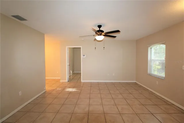 a view of an empty room with chandelier fan