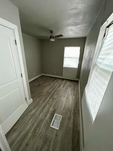 a view of empty room with wooden floor and fan