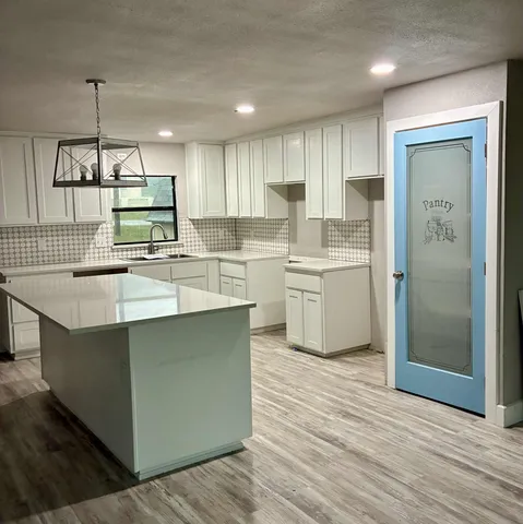 a kitchen with kitchen island a sink a stove a refrigerator and white cabinets