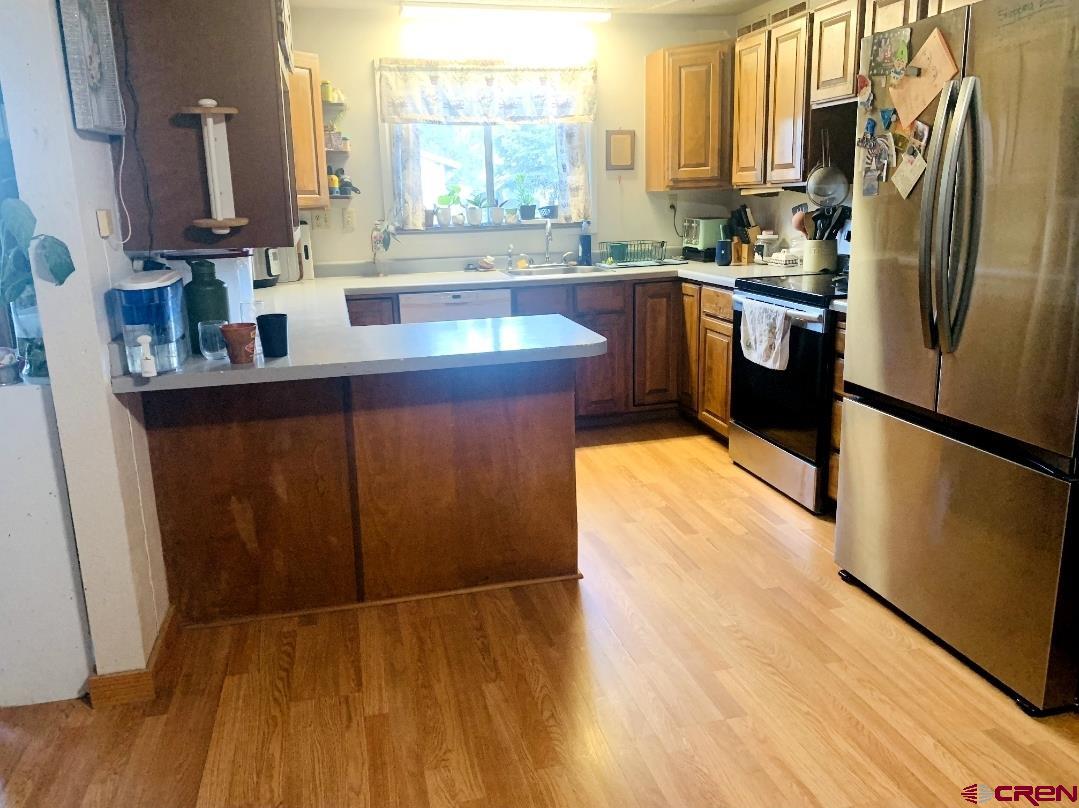 1128 Montana Way Nucla, CO 81424 - Photo 16 of 30 a kitchen with stainless steel appliances granite countertop a refrigerator a sink dishwasher and wooden cabinets with wooden floor