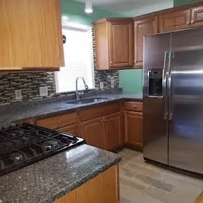 a kitchen with granite countertop a sink stove and refrigerator