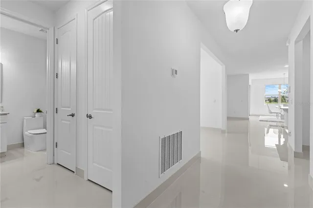 a view of a hallway with wooden floor windows and a bathroom
