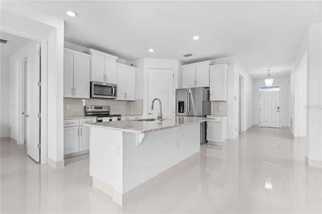a kitchen with kitchen island white cabinets and stainless steel appliances
