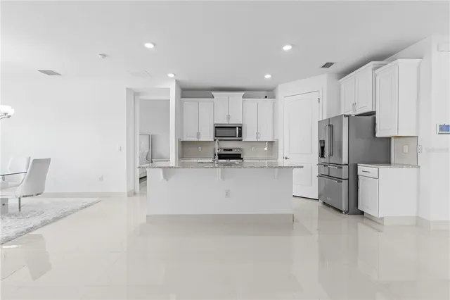 a kitchen with stainless steel appliances a refrigerator sink and white cabinets