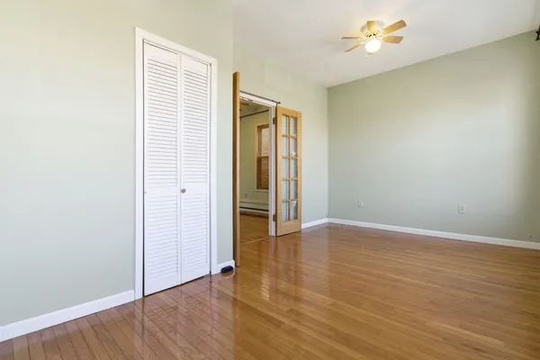an empty room with wooden floor and closet area