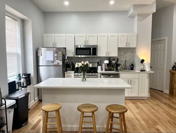 a kitchen with stainless steel appliances a white table chairs refrigerator and microwave