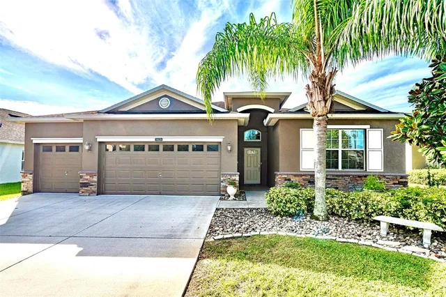 a front view of a house with a garden and palm trees