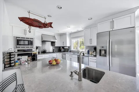 a kitchen view with stainless steel appliances a refrigerator a stove a sink dishwasher a oven with white cabinets and wooden cabinets