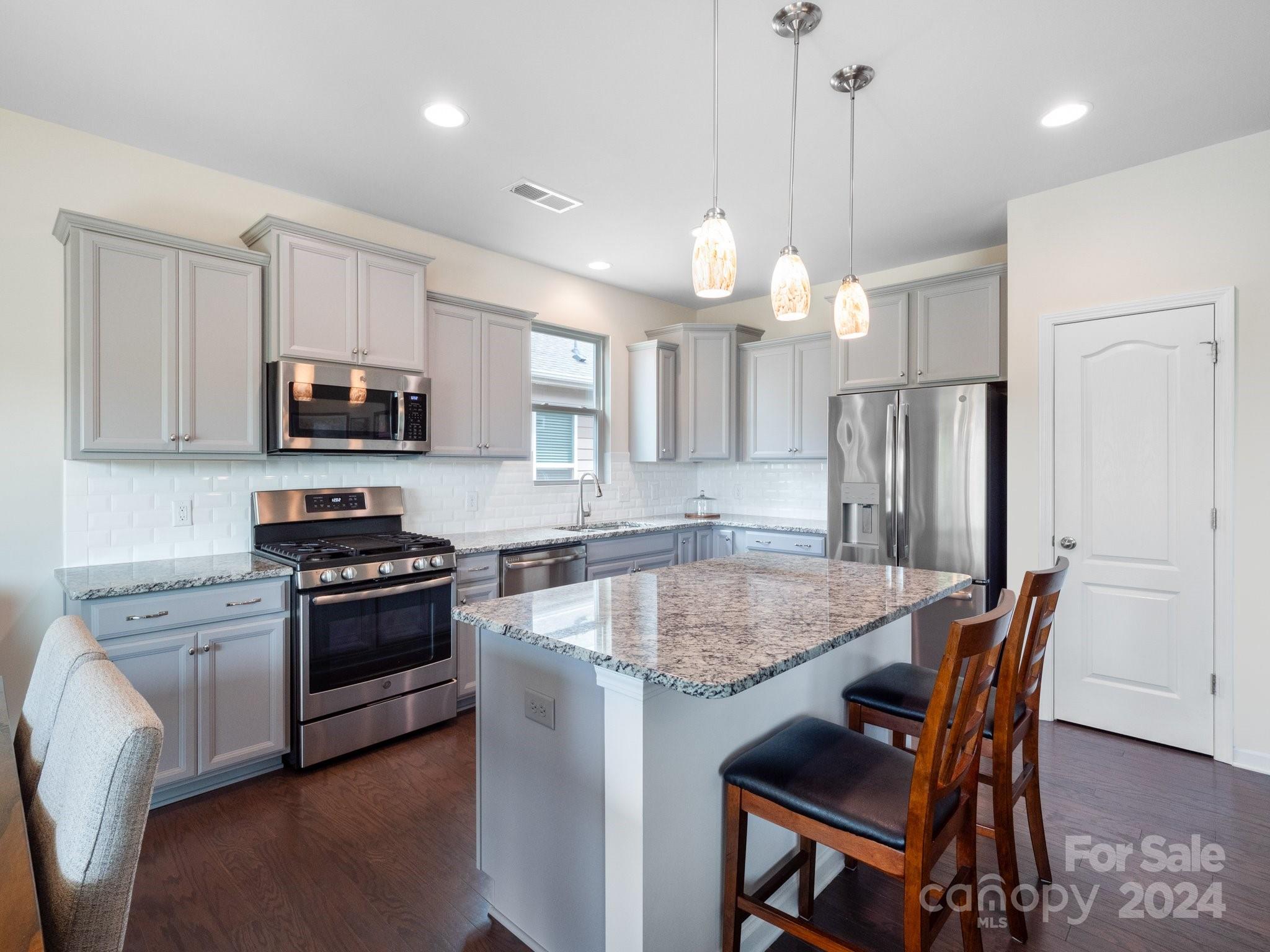 4239 Merrivale Drive Lancaster, SC 29720 - Photo 11 of 33 a kitchen with stainless steel appliances granite countertop a kitchen island hardwood floor sink stove dining table and chairs