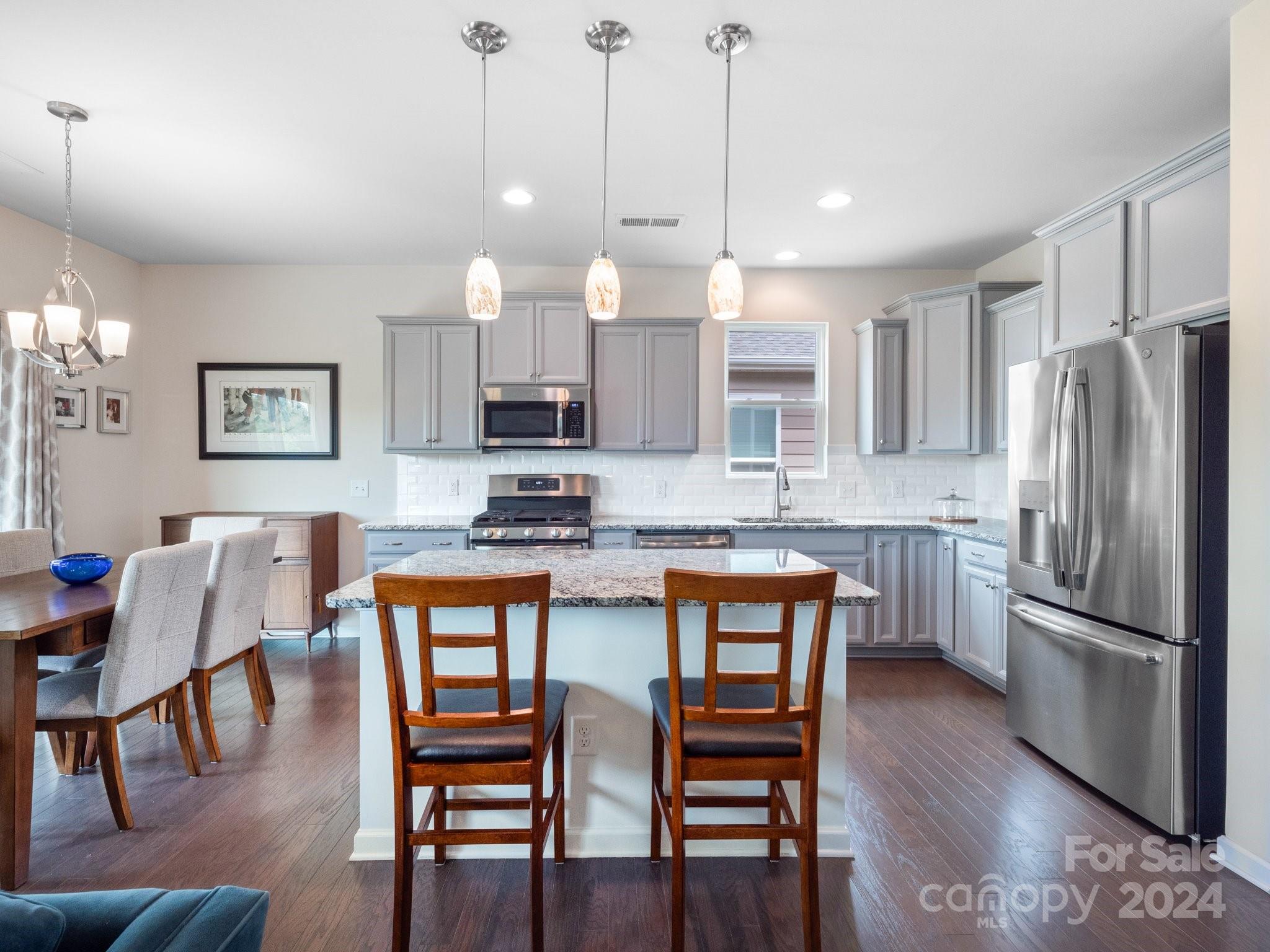 4239 Merrivale Drive Lancaster, SC 29720 - Photo 10 of 33 a kitchen with stainless steel appliances granite countertop a stove a refrigerator a kitchen island a dining table and chairs with wooden floor