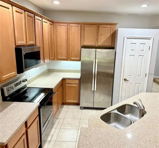 a kitchen with granite countertop a refrigerator stove and sink