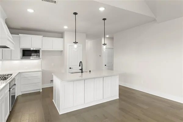 a large white kitchen with stainless steel appliances kitchen island a large counter top and a wooden floors