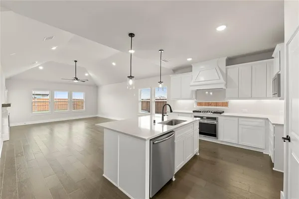 an empty room with wooden floor kitchen electric appliances and windows