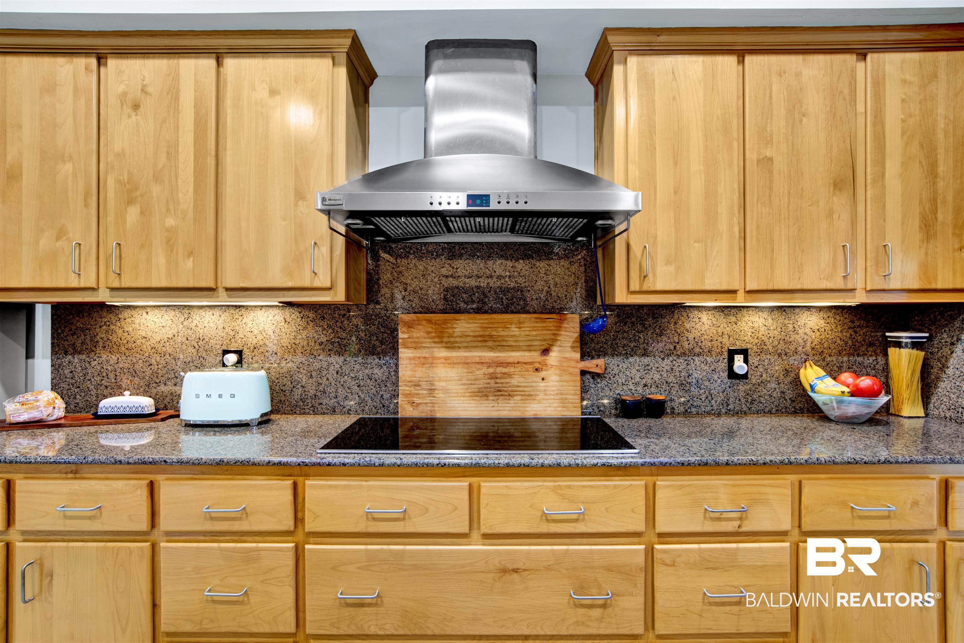 809 Bernard Circle Mobile, AL 36693 - Photo 33 of 75 Kitchen featuring a stainless steel range hood, an electric cooktop, a stone-finish countertop, a coordinating backsplash, and light wood cabinetry with brushed nickel hardware