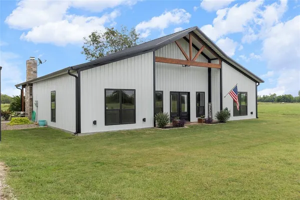 a view of a white house with a big yard and large trees