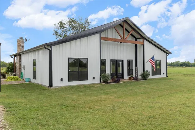 a view of a white house with a big yard and large trees