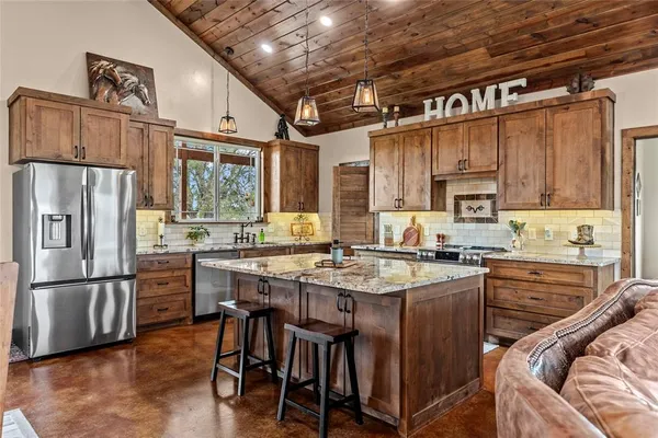 a kitchen with stainless steel appliances granite countertop a refrigerator a stove a sink dishwasher a dining table and chairs with wooden floor
