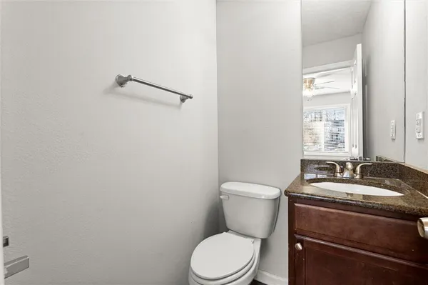 a bathroom with a granite countertop toilet sink and mirror