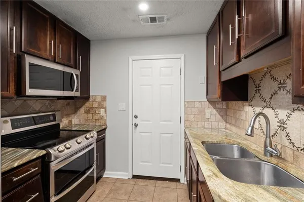 a kitchen with granite countertop a sink stainless steel appliances and cabinets