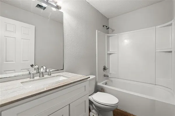 a bathroom with a granite countertop sink a toilet and shower