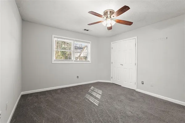 an empty room with windows and fan
