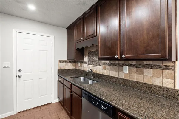 a kitchen with granite countertop stainless steel appliances a sink stove and cabinets