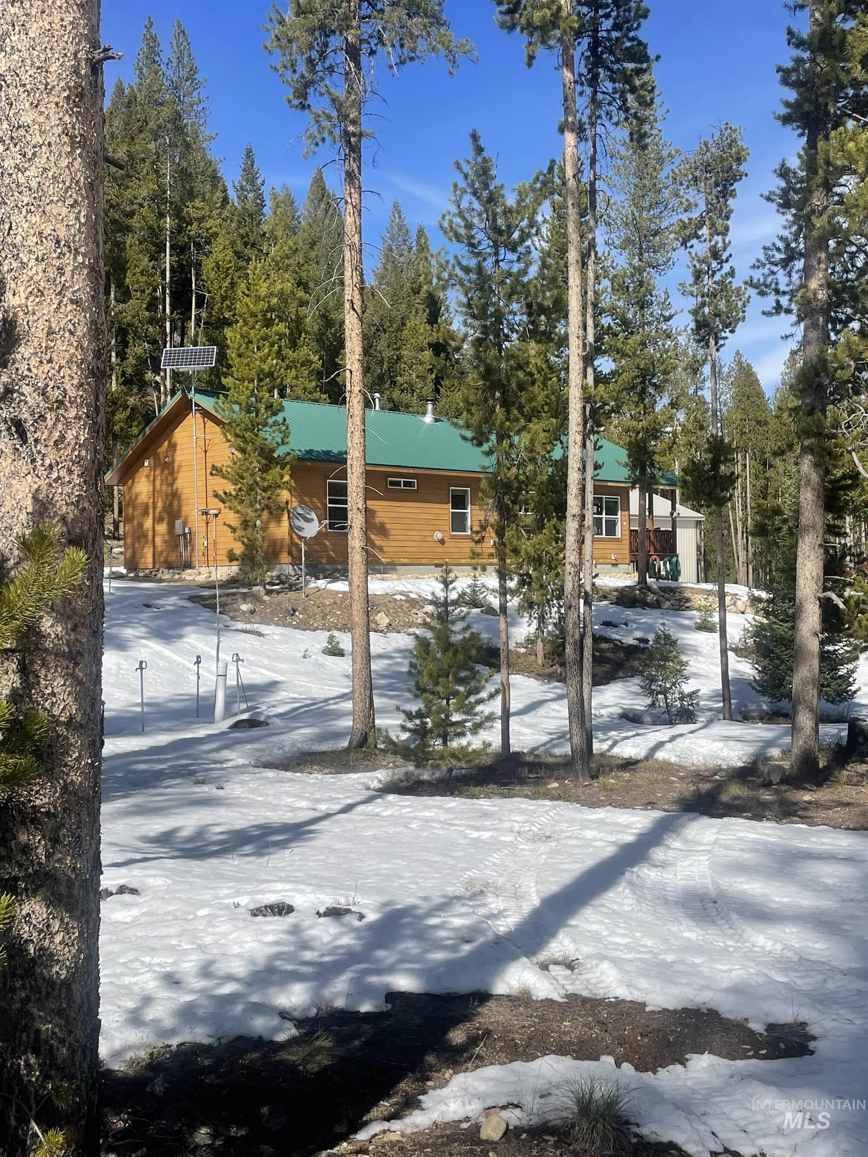 17567 Edwardsburg Road Yellow Pine, ID 83677 - Photo 2 of 11 Wood-sided residence featuring a green metal roof and multiple windows