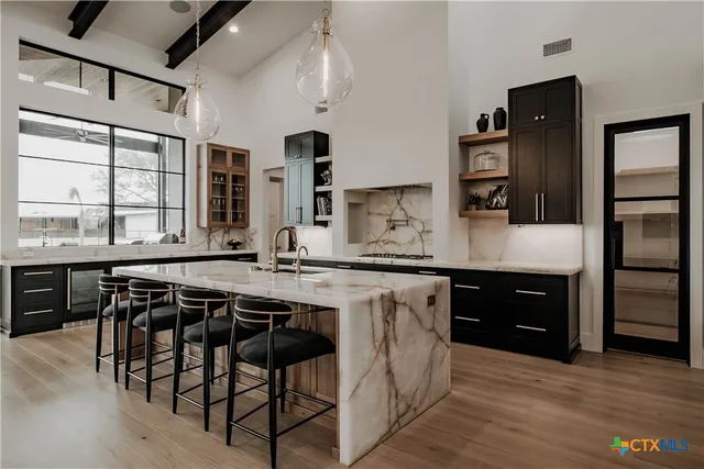 a kitchen with stainless steel appliances granite countertop a stove a sink dishwasher and a refrigerator with wooden floor