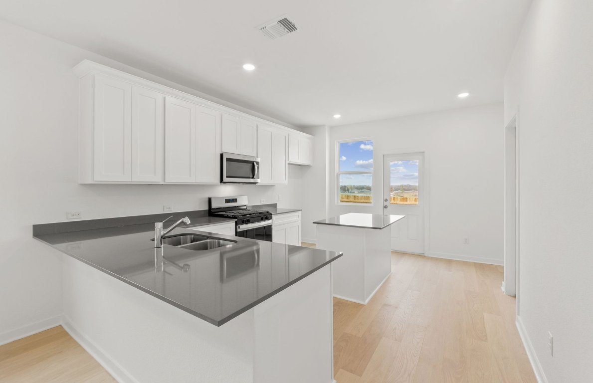 404 Sullivan Way Elgin, TX 78621 - Photo 7 of 23 a kitchen with granite countertop a sink a stove top oven a counter space and cabinets