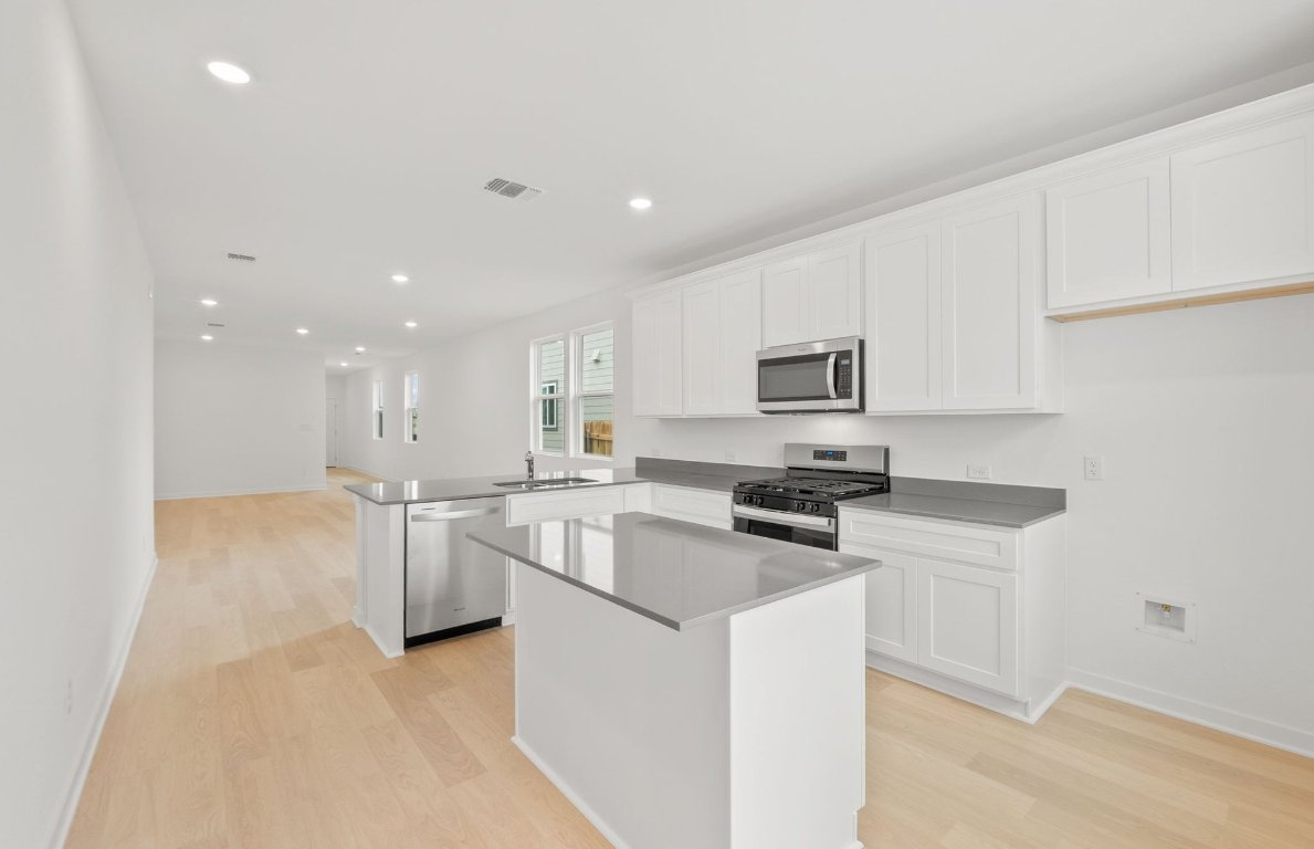 404 Sullivan Way Elgin, TX 78621 - Photo 9 of 23 a kitchen with stainless steel appliances granite countertop a stove top oven a sink a refrigerator and white cabinets