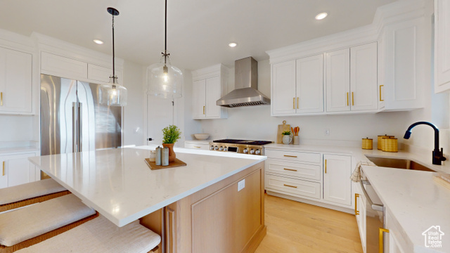 657 North Heritage Street, Unit 9 Mapleton, UT 84664 - Photo 6 of 10 Kitchen featuring light wood-style floors, a center island, light stone counters, wall chimney exhaust hood, and white cabinetry