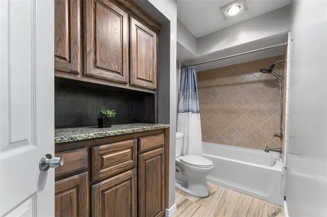 a bathroom with a granite countertop sink a toilet and shower
