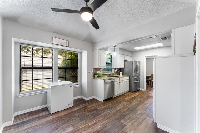 a kitchen with refrigerator and wooden floor