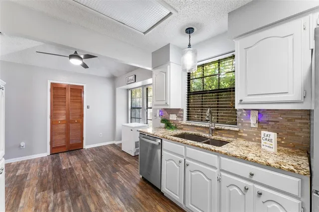 a kitchen with stainless steel appliances granite countertop a sink cabinets and wooden floor