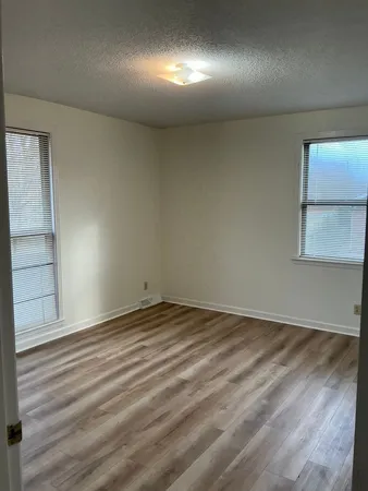 en empty room with wooden floor and windows