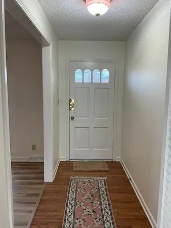 a view of a hallway with wooden floor and a rug