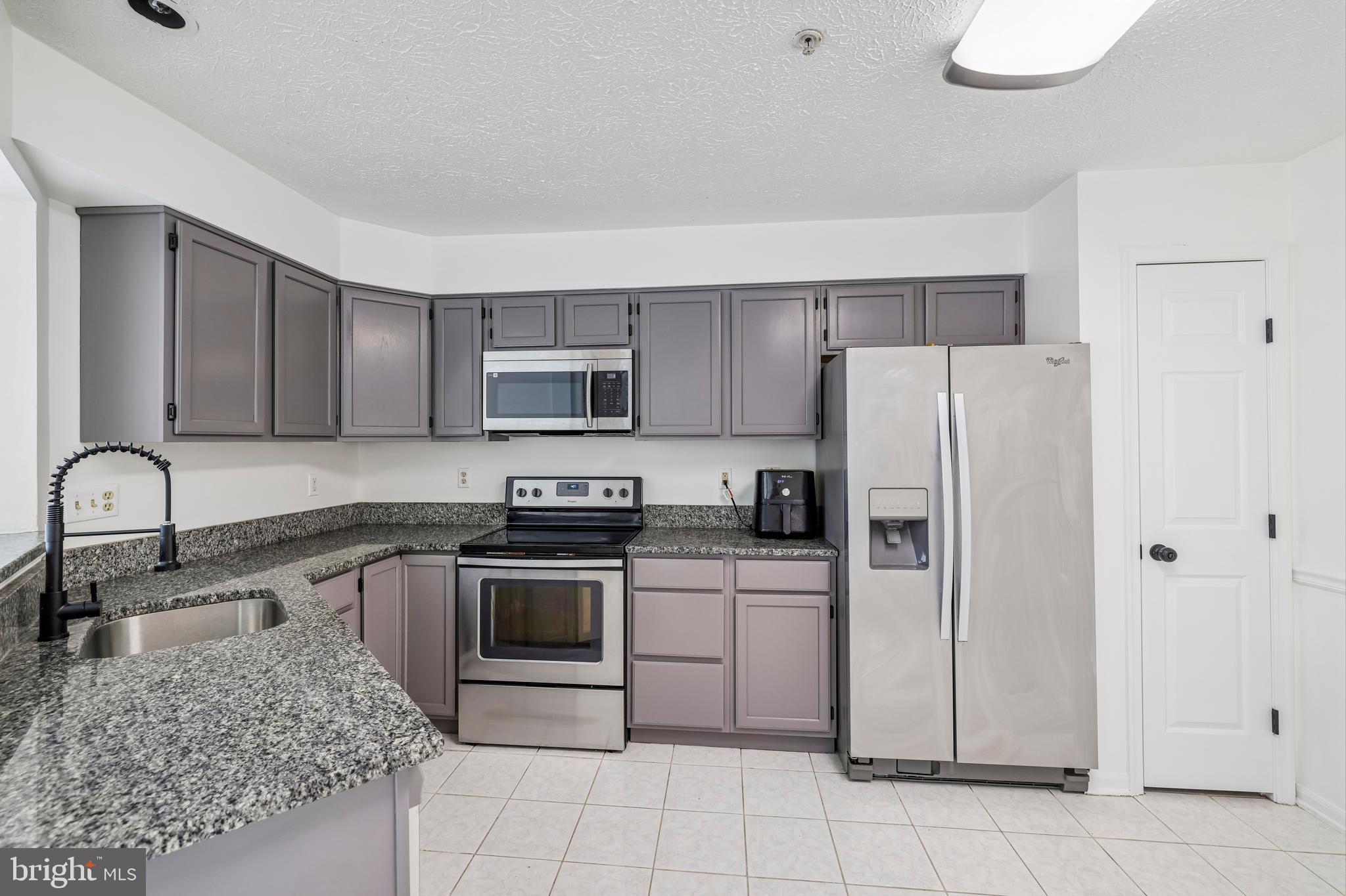 5243 Regal Court Frederick, MD 21703 - Photo 9 of 27 a kitchen with granite countertop a refrigerator sink and stove