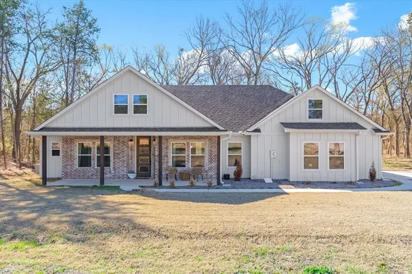 a front view of a house with a yard and large tree