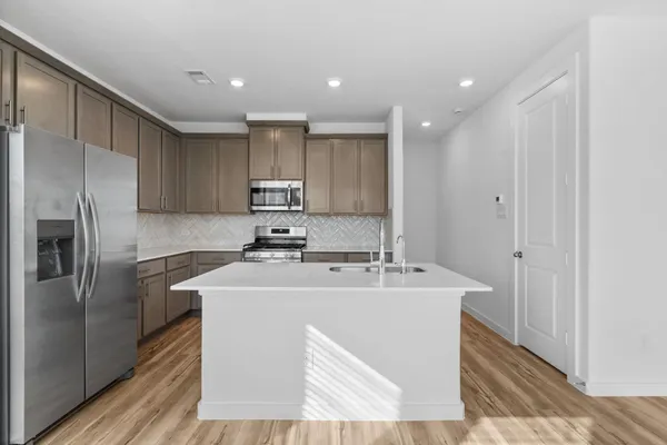 a kitchen with kitchen island a stove a sink and a microwave