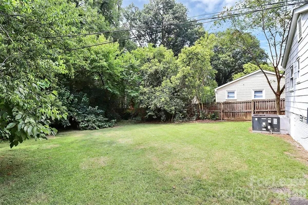 a backyard of a house with plants and large trees