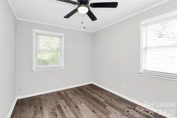a view of empty room with wooden floor and fan