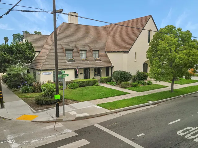 a front view of a house with a yard and potted plants