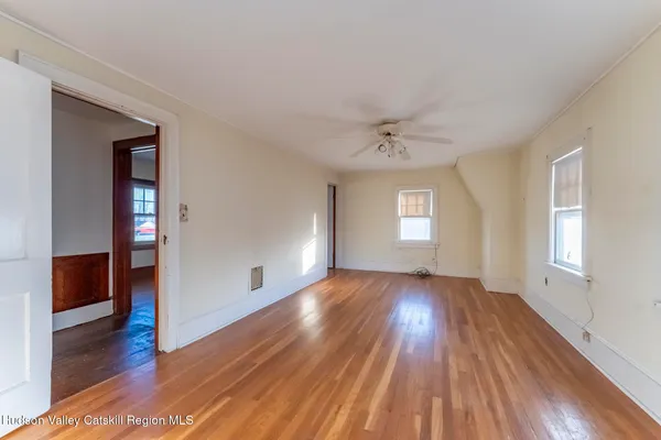 an empty room with wooden floor and windows