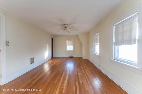 a view of an empty room with wooden floor and a window