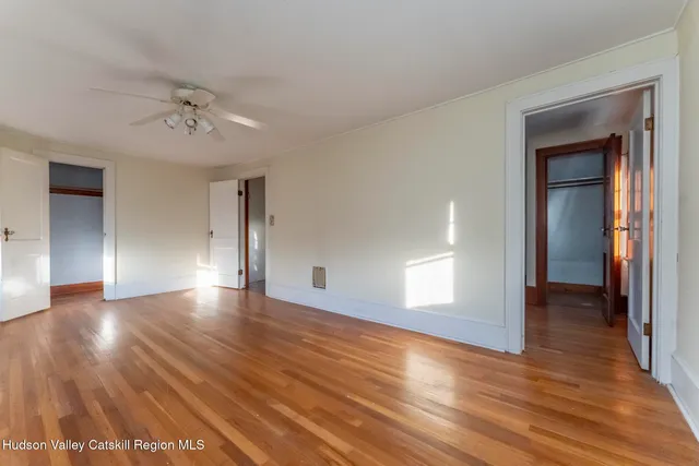 a view of empty room with wooden floor and fan