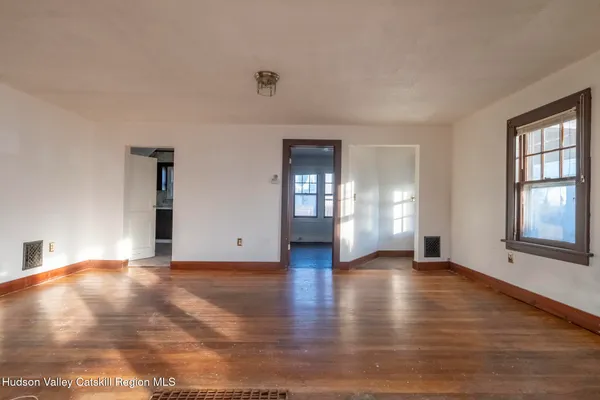 a view of an empty room with window and wooden floor
